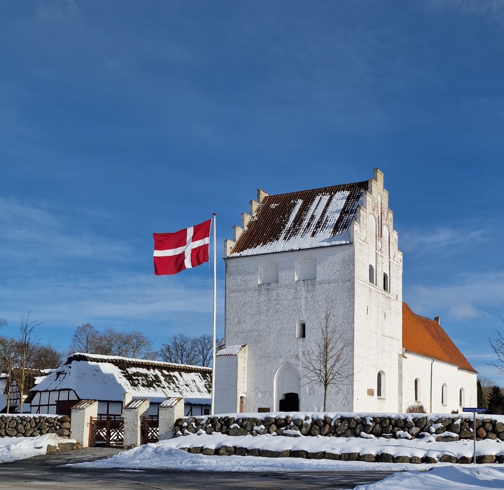 Kølstrup Kirke med flag i snedækket landskab. Foto: Ejnar Zacho Rath